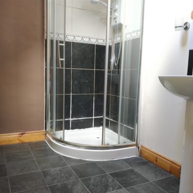 this is an example of a shared bathroom, featuring stone floor and a clean shower